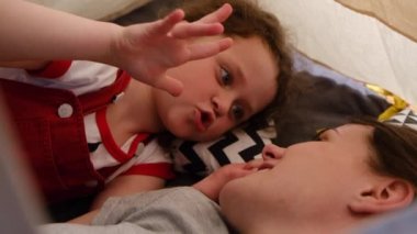 Mutlu anne ve şirin küçük kızın çadırda birbirlerine sarılmalarını, neşeli bir anne ve kızın gülüşünü evde birlikte geçirmelerini. Seçici odak