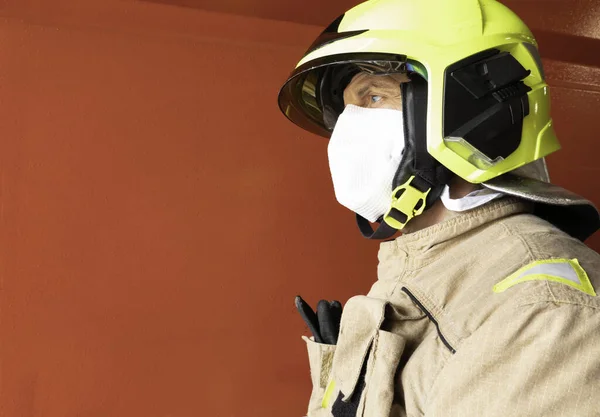 Firefighter equipped with intervention gear, helmet and mask, to protect himself from the covid 19.