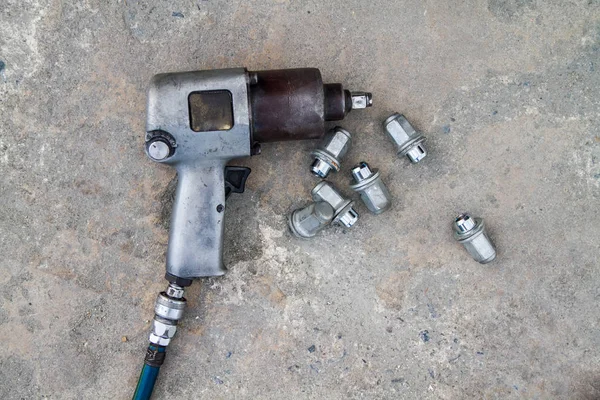 Used air impact wrench and bolts from repair tire on the concrete floor