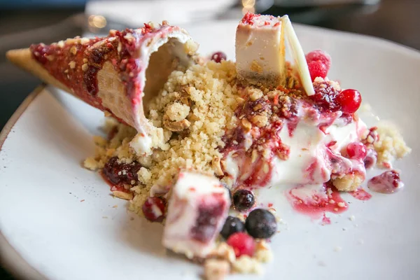 Ice cream cone with crumble and mixed berry on white dish