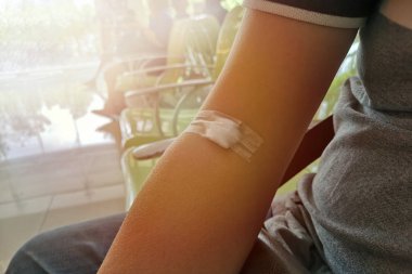 İskoç bandına bağlı Asyalı bir adamın kolu. Sahtekârda kan toplandıktan sonra hastane koridorunda yaralanıp bekliyor..