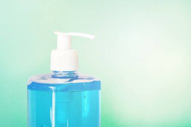 Açık yeşil arka planda, pompa şişesinde mavi el dezenfektanı jeli. İçlerinde alkol de var. Yeni koronavirüsle kirlenmemek için kullanılır..