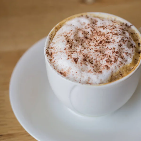 Hot coffee in white cup on table with coffee beans — Stock Photo, Image