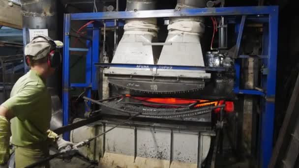 Un operaio fa rotolare un carrello nel forno per la tempra del vetro . — Video Stock