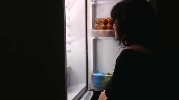 Het meisje doet 's nachts de koelkastdeur open en trekt de taart eruit.. — Stockvideo