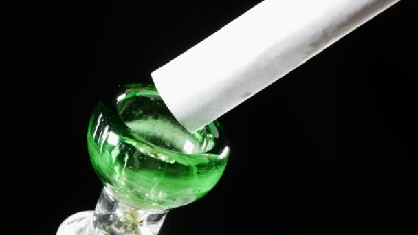 Van verdraaid wit papier, wat marihuana gegoten in een glazen schaal van de hookah. — Stockvideo