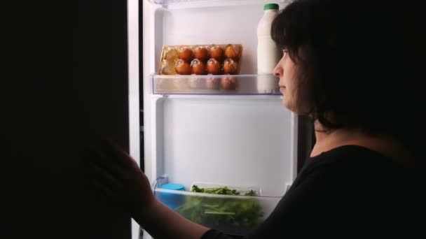 Una mujer recibe una magdalena de la nevera.Abre y cierra la puerta del refrigerador . — Vídeos de Stock