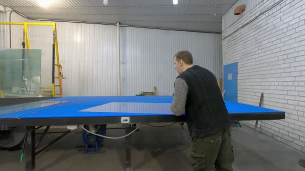 Ein mann schneidet das glas auf dem tisch.glaser bei der arbeit.schneidet und legt auf die theke. — Stockvideo