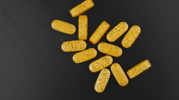 Tablets yellow color with color blotches on a black background slowly rotate. — Stockvideo