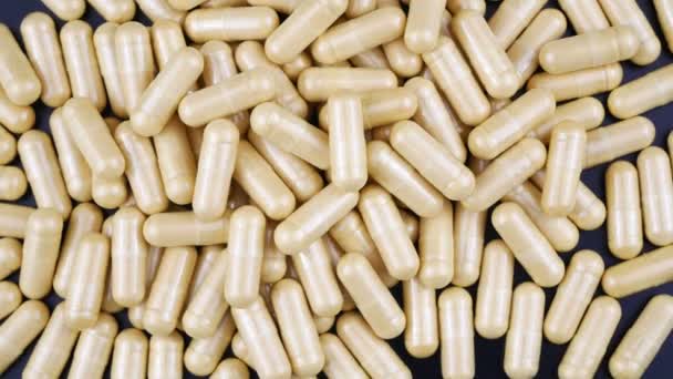 Molte pillole capsule grigio-gialle sul tavolo e ruotano. La vista dall'alto . — Video Stock
