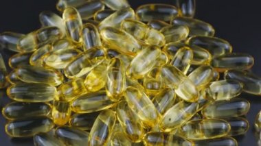 Omega 3 and 6 fish oil.Capsule Golden brown rotate against a dark background.