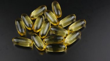 Omega 3 balık yağının kapsülleri koyu bir zemin üzerinde döner..