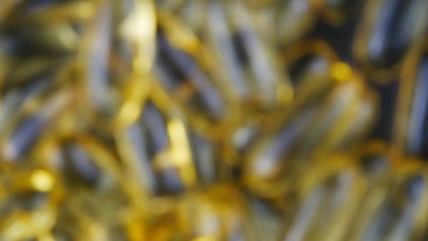 Cápsulas translúcidas doradas de omega 3 sobre un fondo oscuro . — Vídeos de Stock