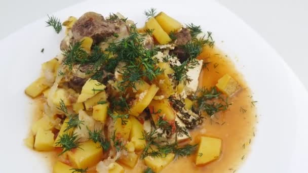Ragoût de bœuf aux pommes de terre rôties garni de légumes verts sur une assiette blanche . — Video