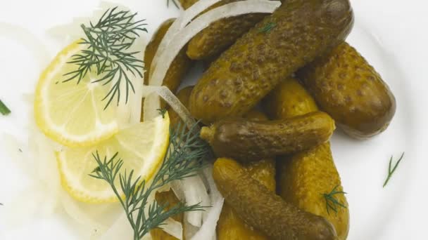 Salty green cucumbers with onions,dill and lemon laying on a white plate. — Stock Video