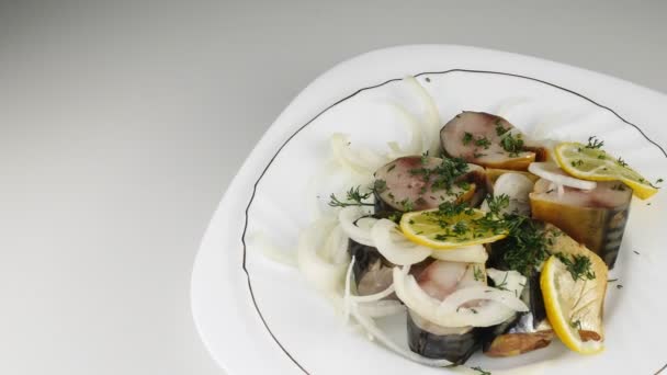 Pescado salado con cebolla sobre un plato blanco.Trozos de caballa, giran en círculo . — Vídeos de Stock