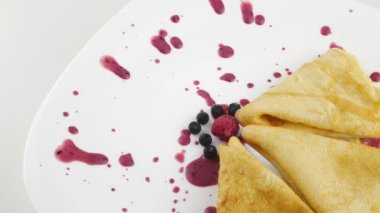 Reçelli krep. Ahududu ve yaban mersini. Beyaz bir tabakta.