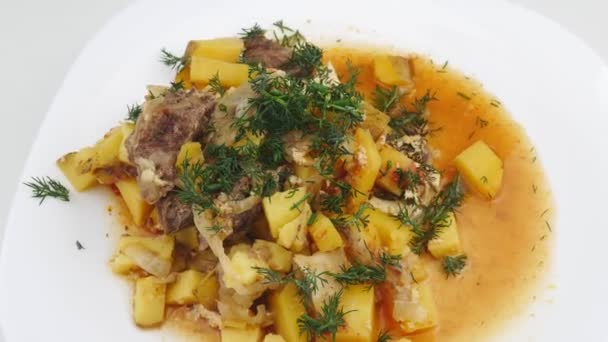 Картофель с овощами, говядиной и зеленью, лежащий на белой тарелке . — стоковое видео