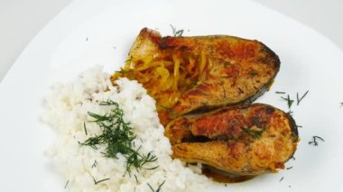 Beyaz pirzolalı kızarmış balık. Kapalı beyaz bir tabakta. Daire şeklinde dönüyor..