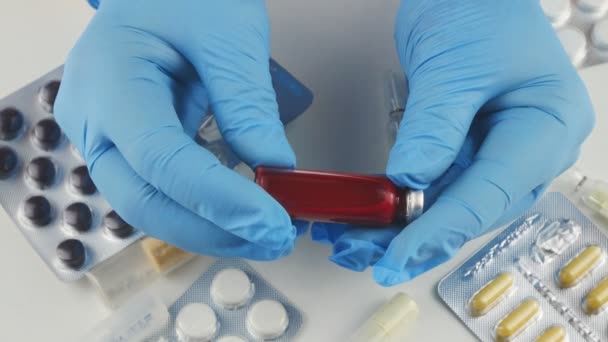 Mãos em azul luvas médicas segurando um frasco de sangue covid 19 . — Vídeo de Stock