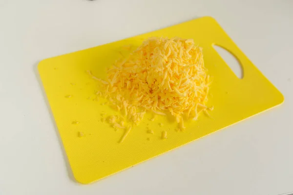 Тертый сыр и терка на тарелке на столе — стоковое фото