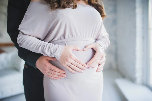Pregnant girl. A man with a woman is waiting for the child, they embrace the tummy. — Stock Photo, Image