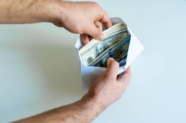 Adamın elleri ile zarf dolu Doları banknot beyaz arka plan üzerinde closeup. Yolsuzluk ve rüşvet kavramı