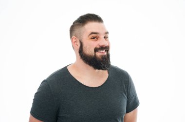 Sevinçle gülümseyen stüdyo çekim mavi t-shirt, kamera geniş bir gülümseme ile seyir Avrupa erkek modeli sakallı. Olumlu duygular, duygu ve reaksiyon