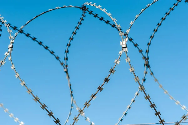 Vue rapprochée de la caméra de sécurité suspendue entre barbelés en prison ou autre objet gardé avec fond bleu ciel. Des méthodes modernes de supervision. Utilisation des nouvelles technologies en matière de sécurité et de sûreté . — Photo