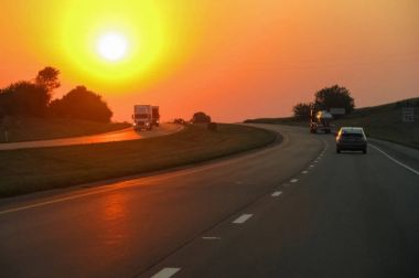 Karayolu ile kamyon ve araba batan güneşin arka plan üzerinde