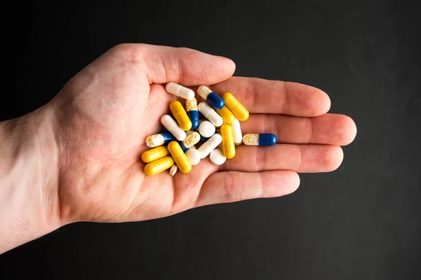 Különböző tabletták, tabletták a kezében, gyógyszerek a fekete bac Jogdíjmentes Stock Fotók