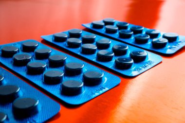 Different tablets, pills in foil blister packs, medications drugs on bronze background