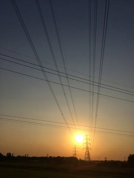 Sunset last light of the day at county with high voltage cables to operate in the dark