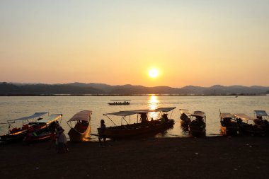 Sangkhlaburi 'de, Kanchanaburi' de, Tayland 'da alacakaranlık gökyüzüne yanaşan turist teknesiyle gün batımı