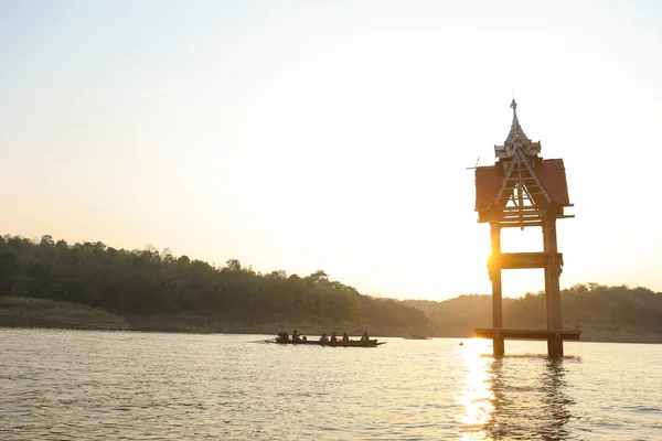 Sangkhlaburi, Kanchanaburi, Tayland 'da alacakaranlıkta turist teknesiyle gün batımında gökte.