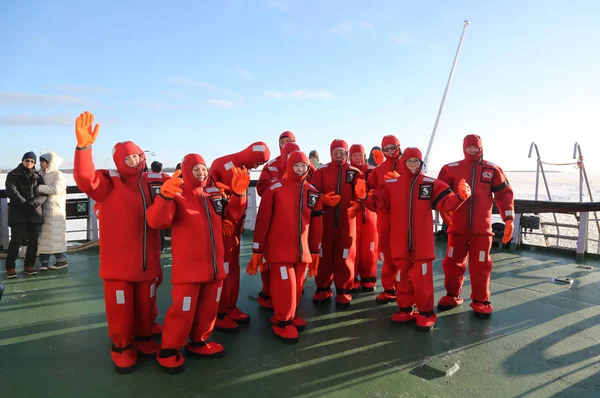 Oidentifierade turister laddade upp med en överlevnad kostym redo till is simma i frysta Östersjön. — Stockfoto