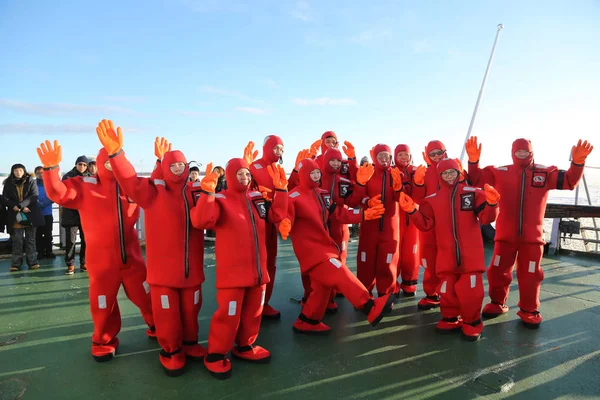 Turistas no identificados preparados con un traje de supervivencia listo para nadar en hielo en el Mar Báltico congelado . — Foto de Stock