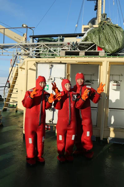 Turistas no identificados preparados con un traje de supervivencia listo para nadar en hielo en el Mar Báltico congelado . — Foto de Stock