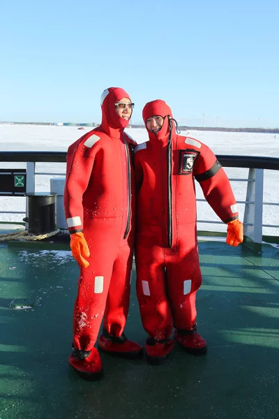 Turistas no identificados preparados con un traje de supervivencia listo para nadar en hielo en el Mar Báltico congelado . —  Fotos de Stock