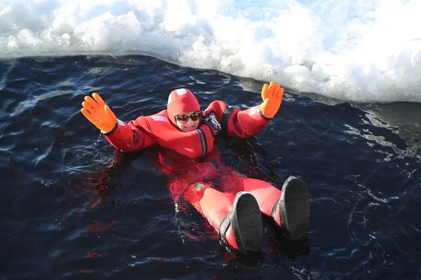Turistas não identificados com um fato de sobrevivência nadam no mar Báltico congelado . — Fotografia de Stock