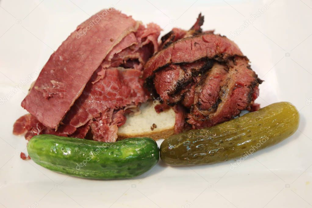 Famous Corned Beef and Pastrami on rye sandwich served with pickles in New York Deli