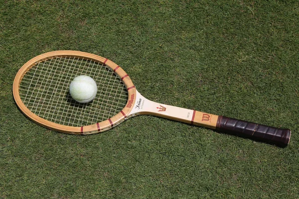 老式威尔逊杰克 · 克雷默网球拍和古色古香的白色网球球对草地网球场. — 图库照片