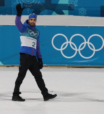 Pyeongchang, Güney Kore 18 Şubat 2018: Olimpiyat şampiyonu Fransa'nın Martin Fourcade Alpensia Biatlon merkezinde 2018 Kış Olimpiyatları'nda biatlon erkekler 15 km toplu çıkış zafer kutluyor.