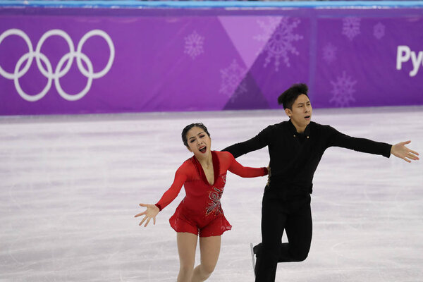 ГАНГНЁНГ, ЮЖНАЯ КОРЕЯ - 15 февраля 2018 года: Серебряные призеры Вэньцзин Суй и Конг Хань из Китая выступают в парном конькобежном спорте на зимних Олимпийских играх 2018 года в Ледяной Арене Каннын
