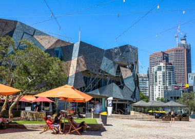 MELBOURNE, AUSTRALYA - 21 HAZİRAN 2019: Ziyaretçiler Melbourne, Avustralya 'daki Federasyon Meydanı' nda güneşli bir günün tadını çıkarıyorlar