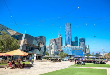 MELBOURNE, AUSTRALYA - 21 HAZİRAN 2019: Ziyaretçiler Melbourne, Avustralya 'daki Federasyon Meydanı' nda güneşli bir günün tadını çıkarıyorlar