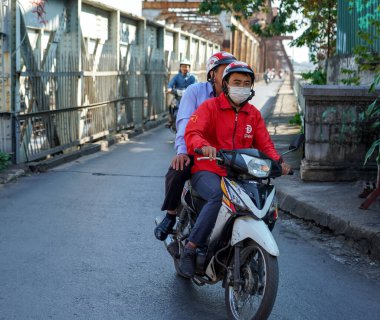 HANOI, VIETNAM - 28 Ekim 2019: Hanoi 'de Hong (Kızıl) nehri üzerinden Long Bien Köprüsü' nden geçen motosikletli insanlar. Köprü Fransız mimar Gustave Eiffel tarafından tasarlandı.