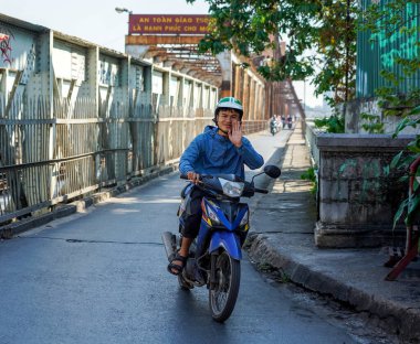 HANOI, VIETNAM - 28 Ekim 2019: Hanoi 'de Hong (Kızıl) nehri üzerinden Long Bien Köprüsü' nden geçen motosikletli insanlar. Köprü Fransız mimar Gustave Eiffel tarafından tasarlandı.