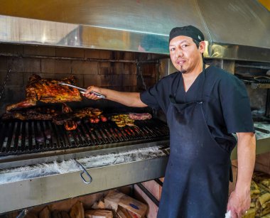 USHUAIA, ARGENTINA - 5 Şubat 2020: Yerel aşçı popüler Arjantin restoranında geleneksel parrillo barbekü eti ve sosis hazırlıyor
