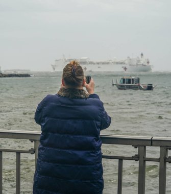 NEW YORK - 30 Nisan 2020: Brooklyn sahilindeki izleyiciler, Coronavirus hastalarıyla ilgilendikten bir ay sonra New York 'tan ayrılan USNS Comfort Hastane Gemisi olarak fotoğraf çekiyorlar